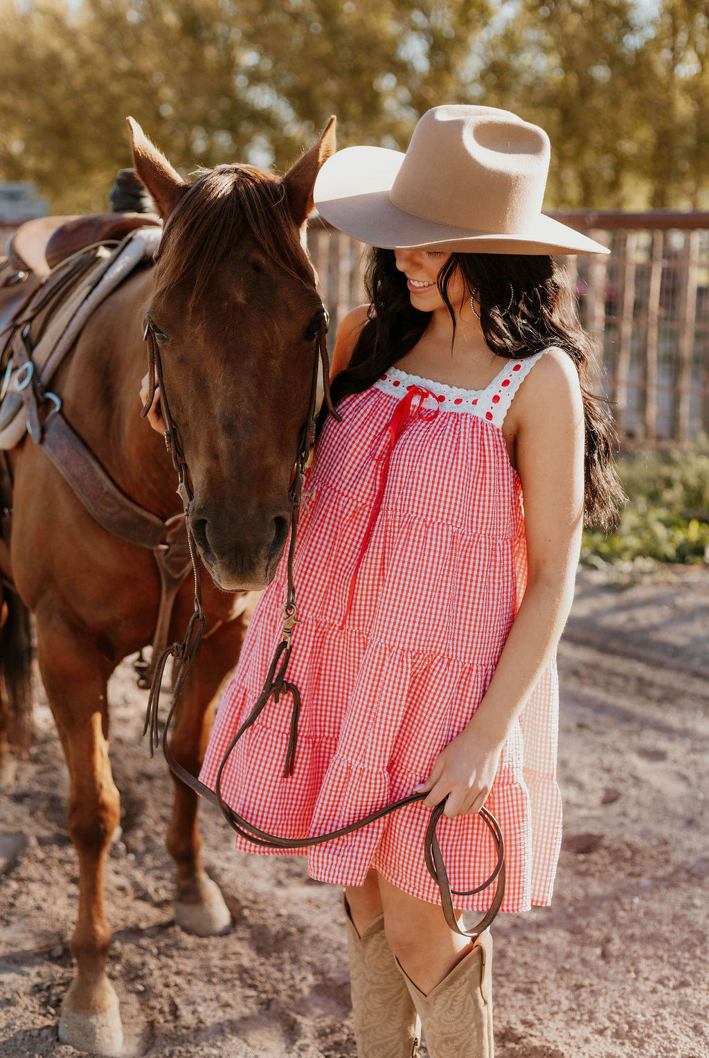 Close up of a horse and a woman wearing the Sweet Land of Liberty Gingham Dress while holding its saddle lace
