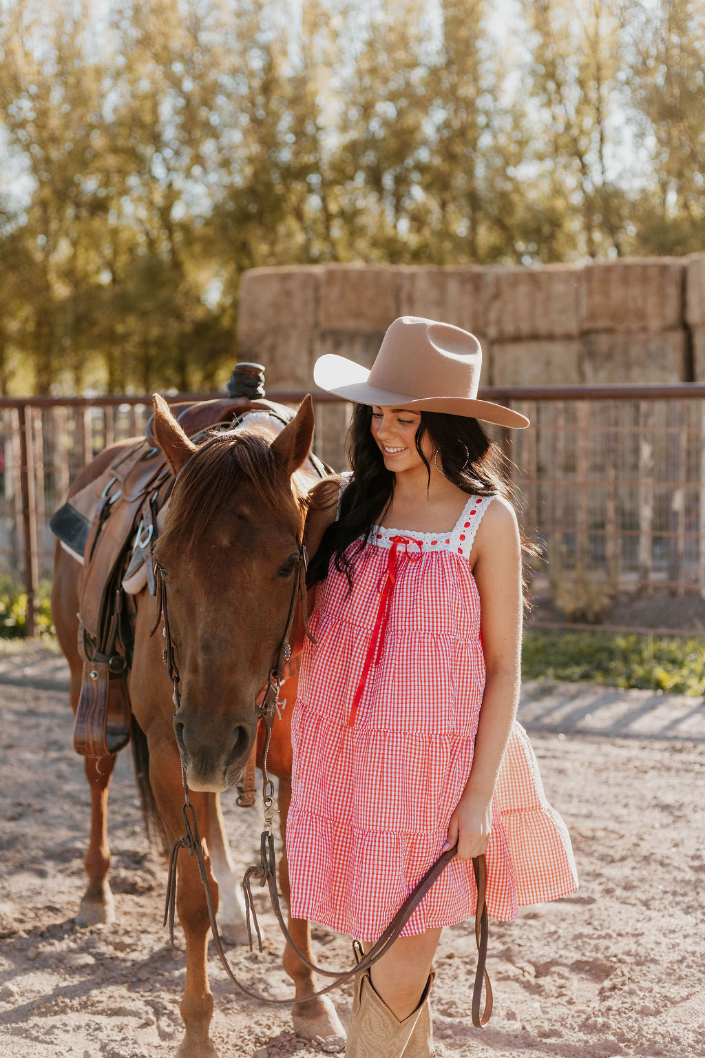 Close up of a horse and a woman wearing the Sweet Land of Liberty Gingham Dress while holding its saddle lace