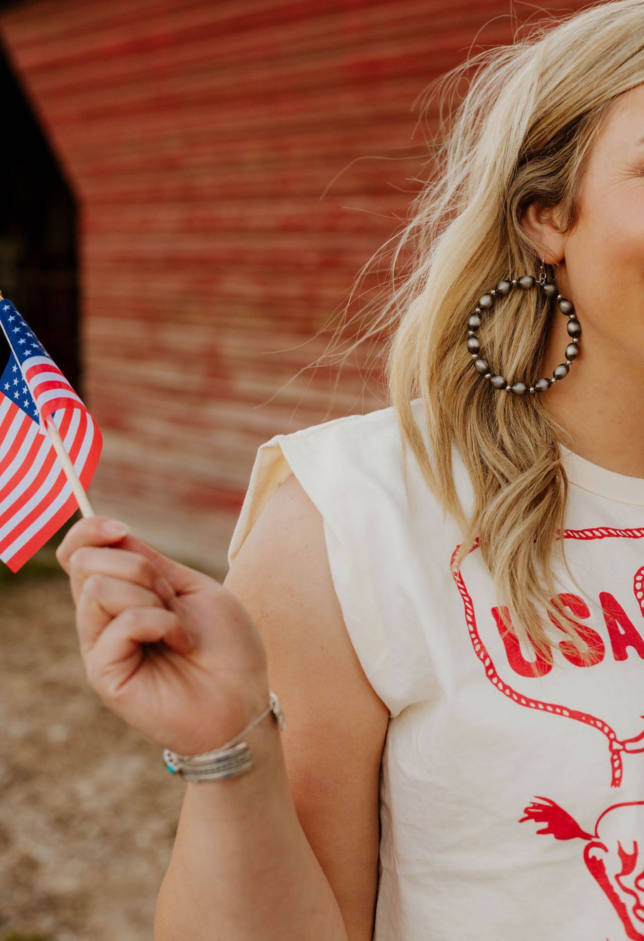 Woman wearing USA Rodeo Team Muscle Tank while holding an American flag